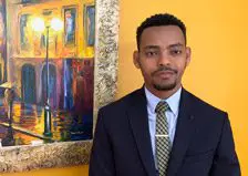 A man in a suit and tie standing next to a painting.